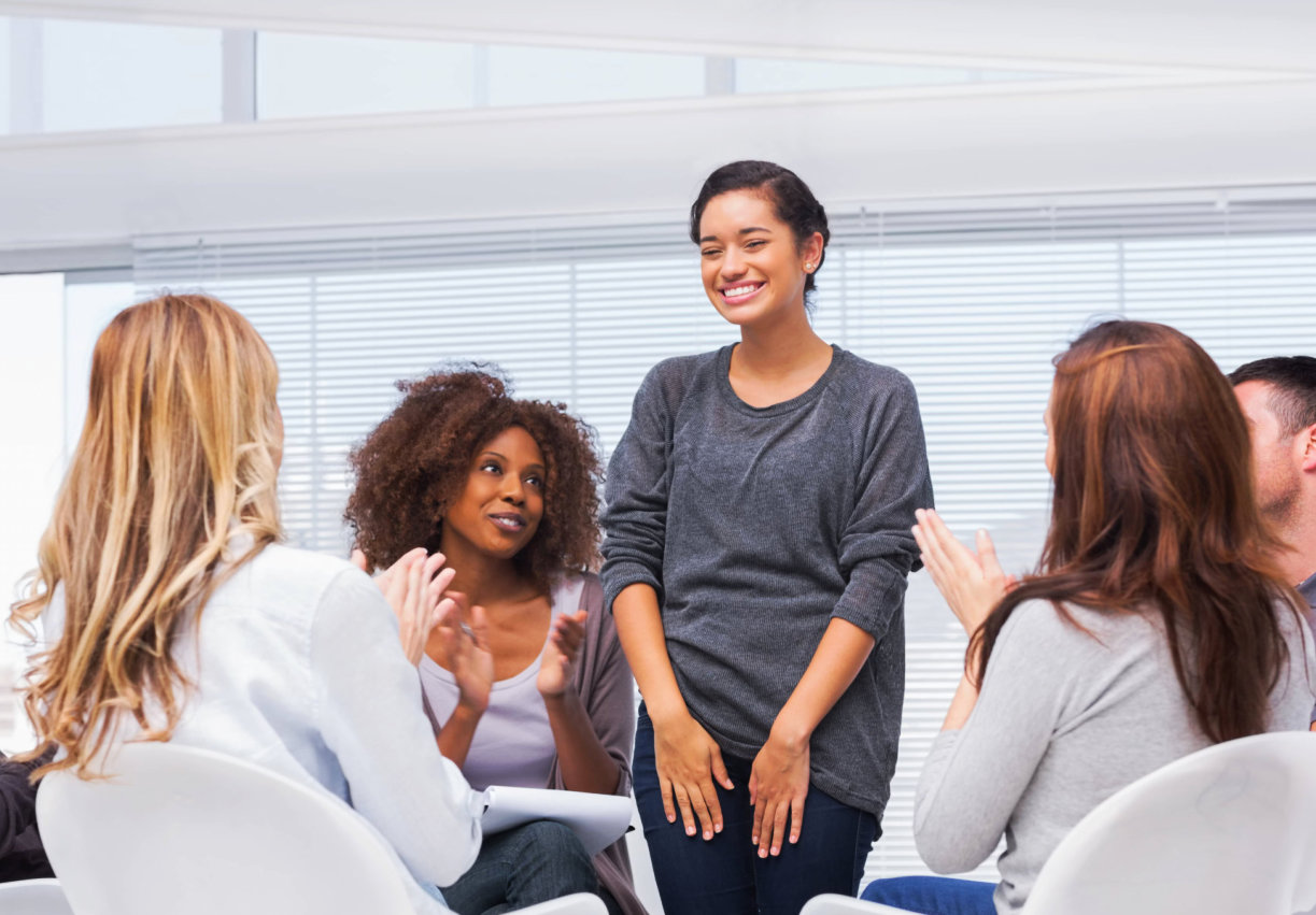 woman smiling in front of her support group